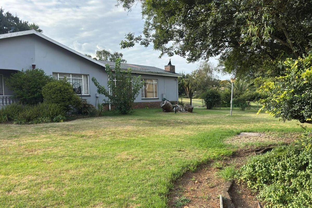 A view of the rear exterior of the commercial property, featuring a large lawn area and established garden surroundings.