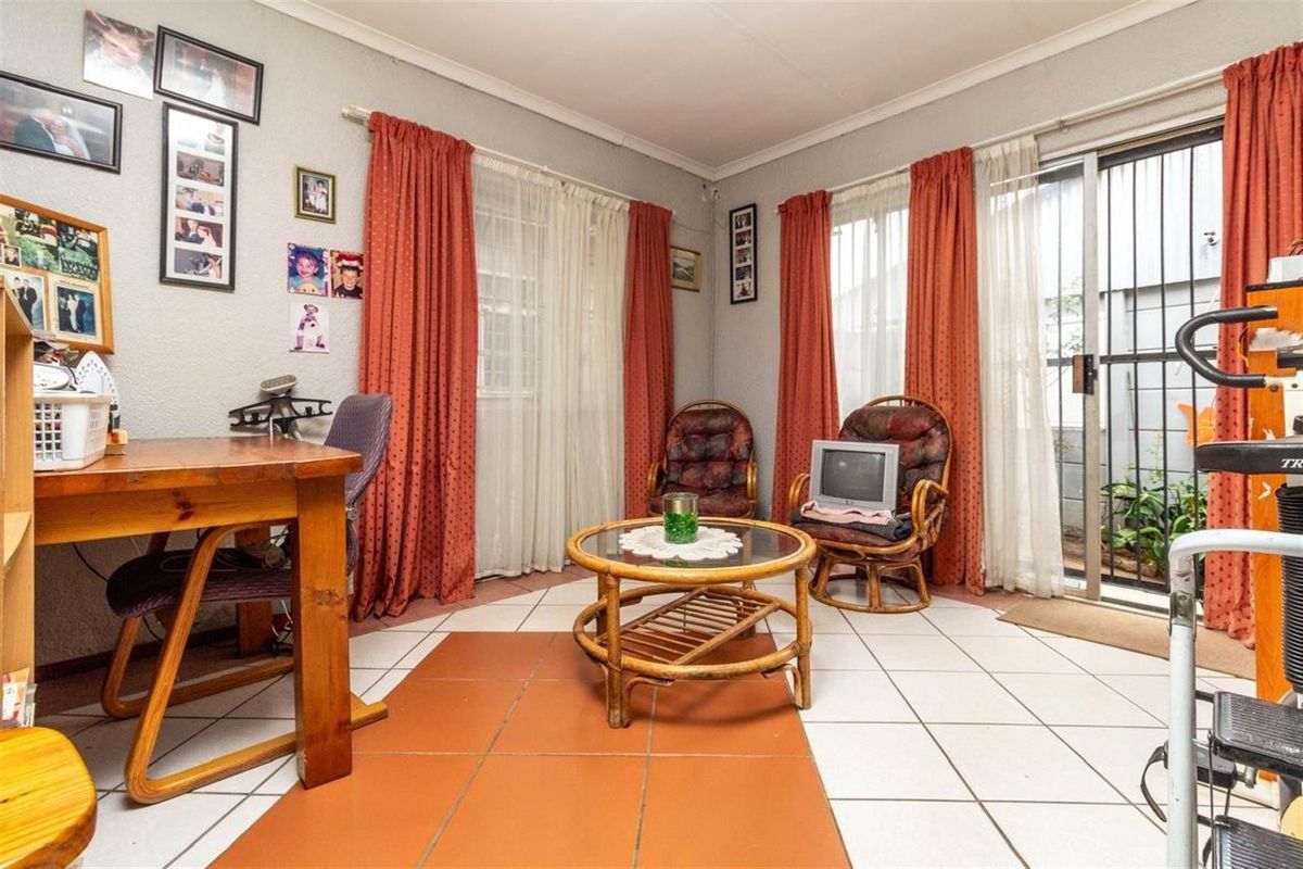 A functional living area featuring tiled flooring and sliding glass doors with security gates, providing direct access to the exterior.