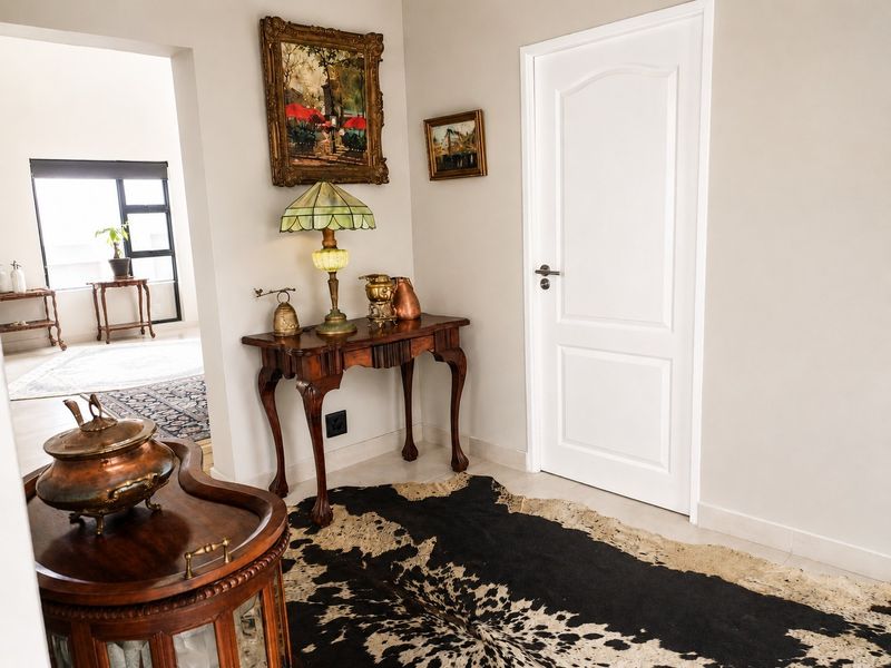 A well-maintained hallway featuring neutral wall finishes, tiled flooring, and a classic internal door leading to adjacent living spaces.