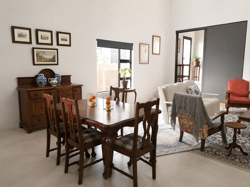 A bright and spacious open-plan living and dining area featuring neutral tiled flooring, large windows, and a modern sliding door transition.