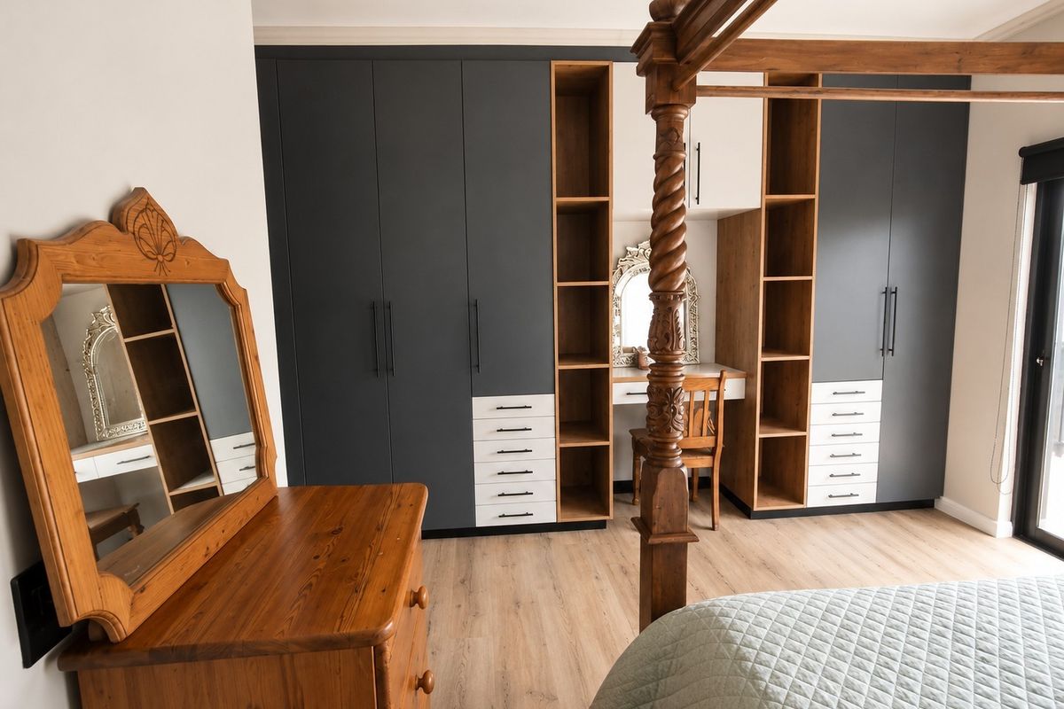 A well-appointed bedroom featuring modern built-in cupboards with integrated vanity shelving, laminate flooring, and a sliding door providing natural light.