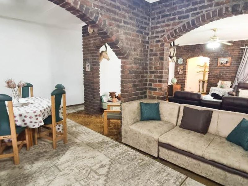 Open-plan living and dining area featuring distinctive exposed brick arches and walls, providing a rustic aesthetic with potential for modern updates.