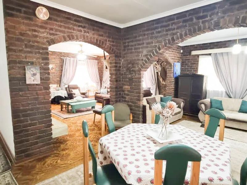 Spacious open-plan living and dining area featuring distinctive exposed brick arches and walls, offering a traditional aesthetic with potential for modern updates.