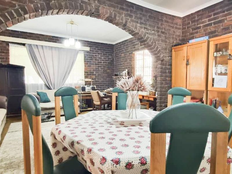 Open plan living and dining area featuring distinctive exposed brick walls and a prominent brick archway connecting the two spaces.