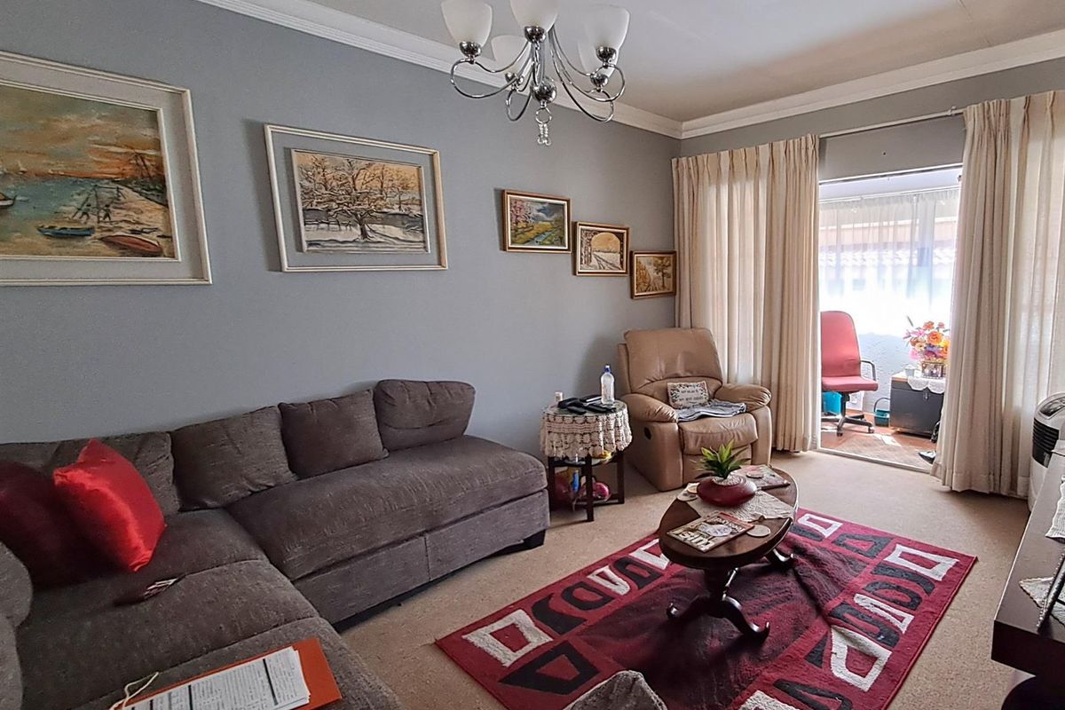A comfortable living room featuring neutral wall tones, crown molding, and direct access to an adjoining balcony through sliding glass doors.