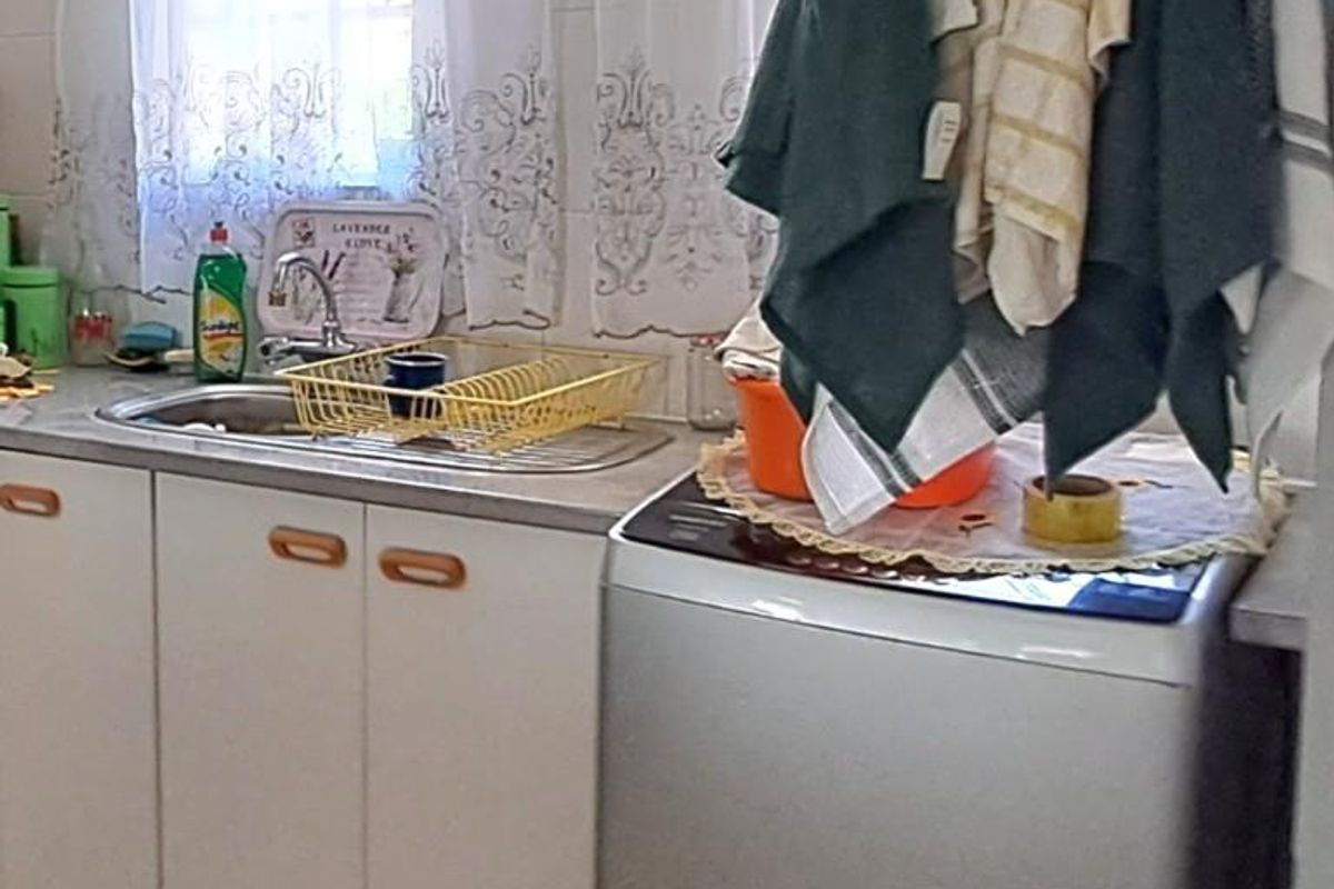 A functional kitchen area featuring white cabinetry, a stainless steel sink, and dedicated space for laundry appliances.