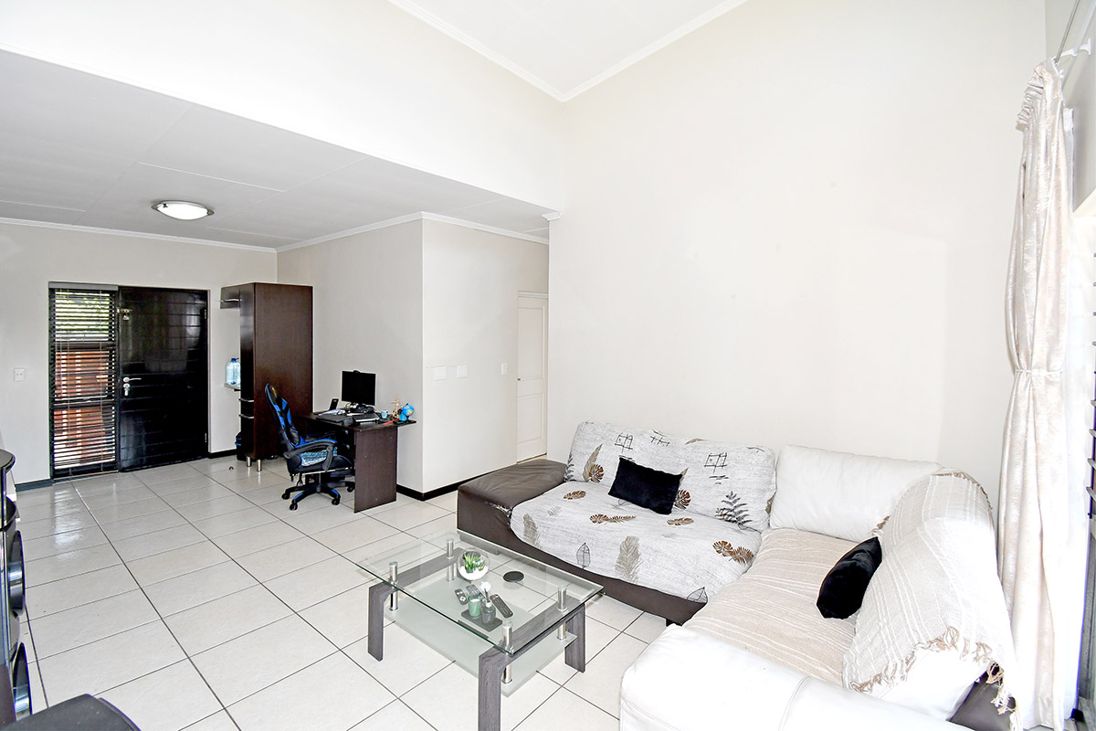 A spacious living area featuring neutral tiled flooring and a bright, open-plan layout with direct access to the main entrance.