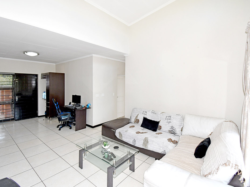 A spacious living area featuring neutral tiled flooring and a bright, open-plan layout with direct access to the main entrance.