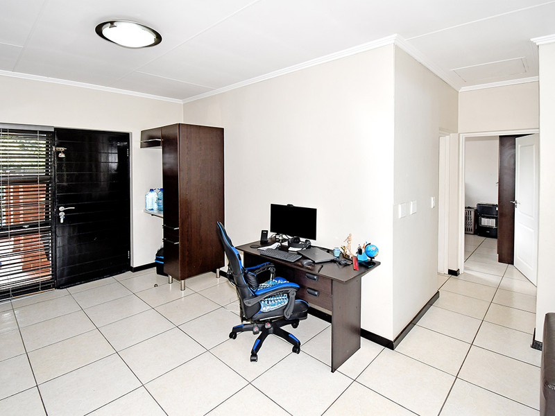 Entrance area featuring tiled flooring, a secure entrance door with security gate, and access to adjacent rooms through internal doorways.