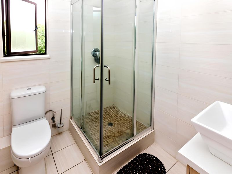A clean, modern bathroom featuring a glass-enclosed shower, a white ceramic toilet, and a contemporary vessel sink vanity.