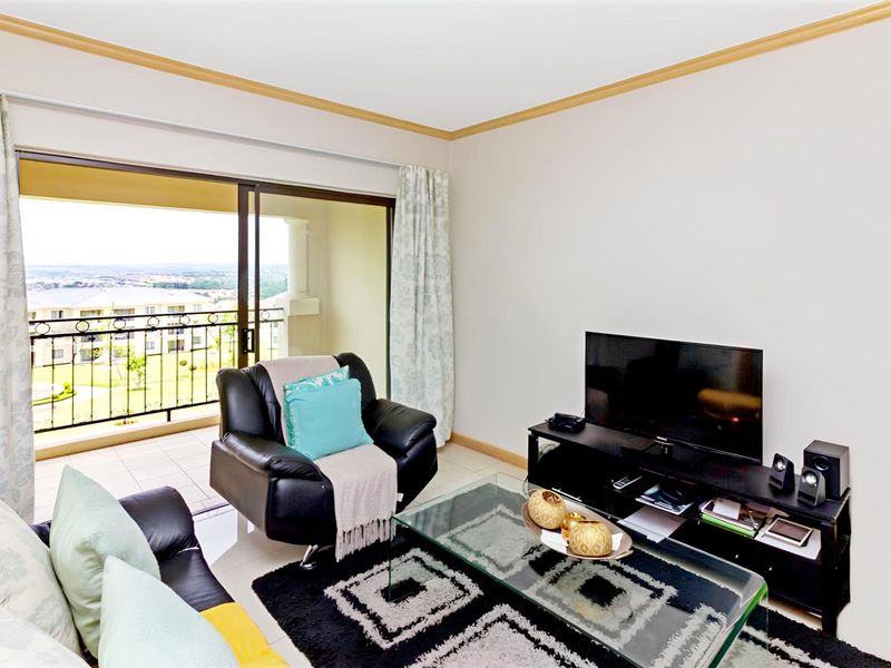 A comfortable living room featuring tiled flooring and large sliding glass doors that open onto a balcony with scenic views.