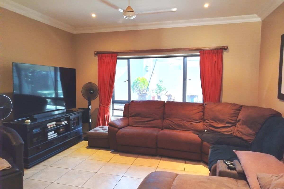 A living room featuring tiled flooring, recessed downlights, and a ceiling fan, providing a functional and comfortable space for relaxation.