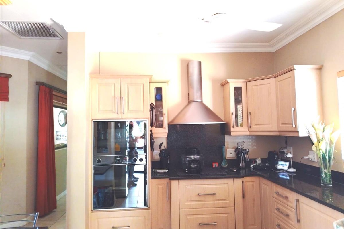 A functional kitchen featuring light wood cabinetry, granite countertops, a built-in oven, and a stainless steel extractor fan.