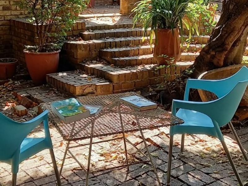 A charming outdoor patio area featuring rustic brick paving, tiered brick steps, and structural brick pillars, creating a cozy and private courtyard space.