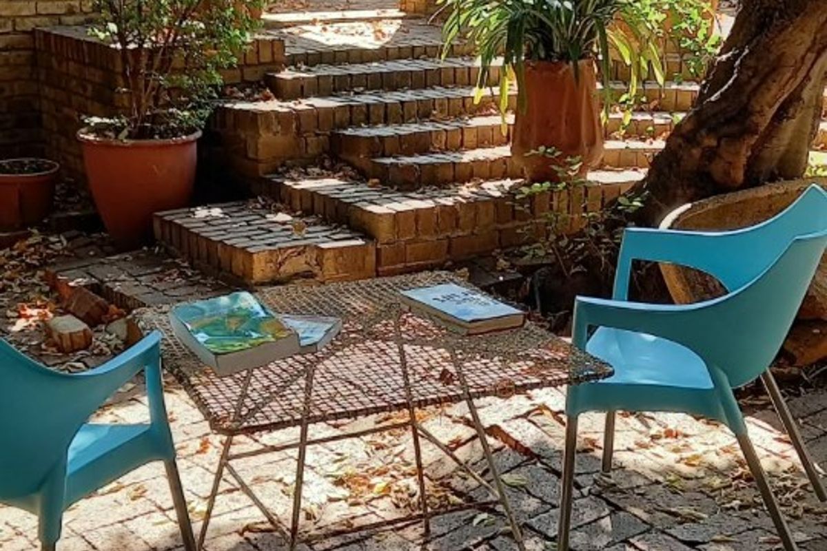 A charming outdoor patio area featuring rustic brick paving, tiered brick steps, and structural brick pillars, creating a cozy and private courtyard space.