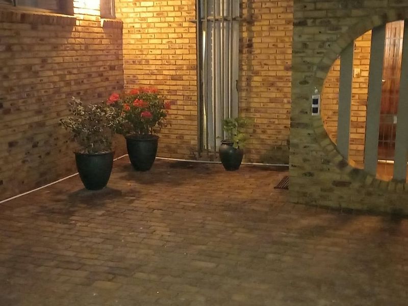 Front entrance area featuring a face brick facade, paved driveway, and a distinctive circular architectural window detail.