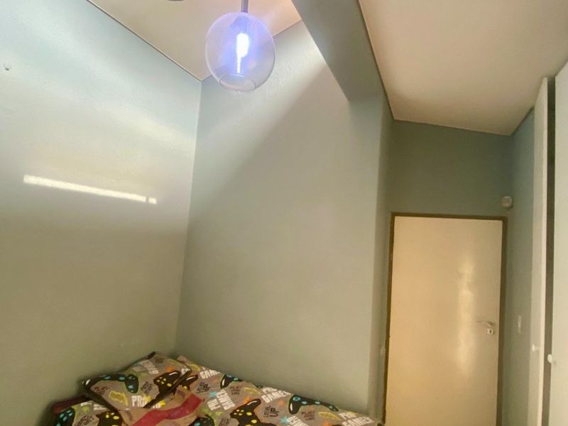 A bedroom featuring a high ceiling, a modern pendant light fixture, and a built-in cupboard.