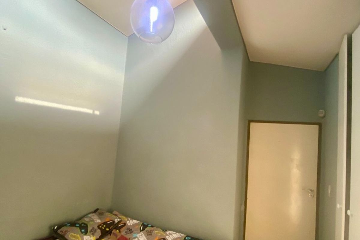 A bedroom featuring a high ceiling, a modern pendant light fixture, and a built-in cupboard.