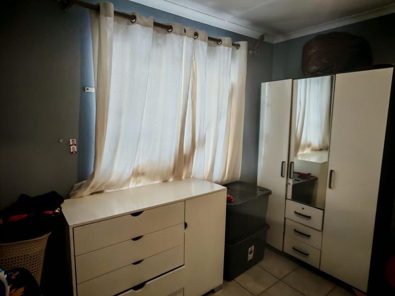 A bedroom featuring tiled flooring, a window with curtain rod, and built-in style cabinetry.