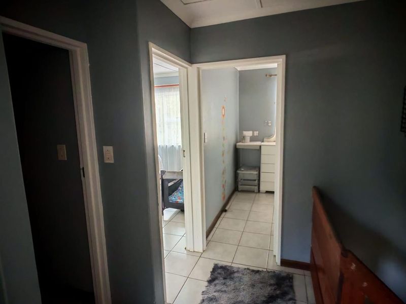 A functional hallway providing access to multiple rooms, featuring tiled flooring and neutral wall finishes.