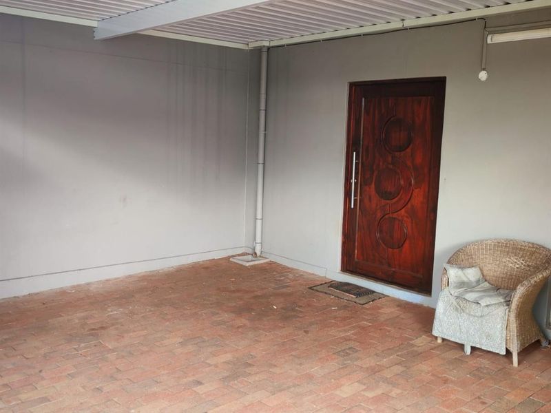 A covered patio area featuring brick paving and a solid timber front entrance door.