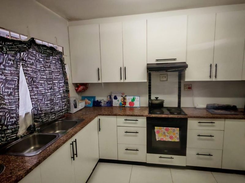 A functional kitchen featuring white cabinetry, granite-look countertops, a double stainless steel sink, and a built-in oven with an extractor fan.
