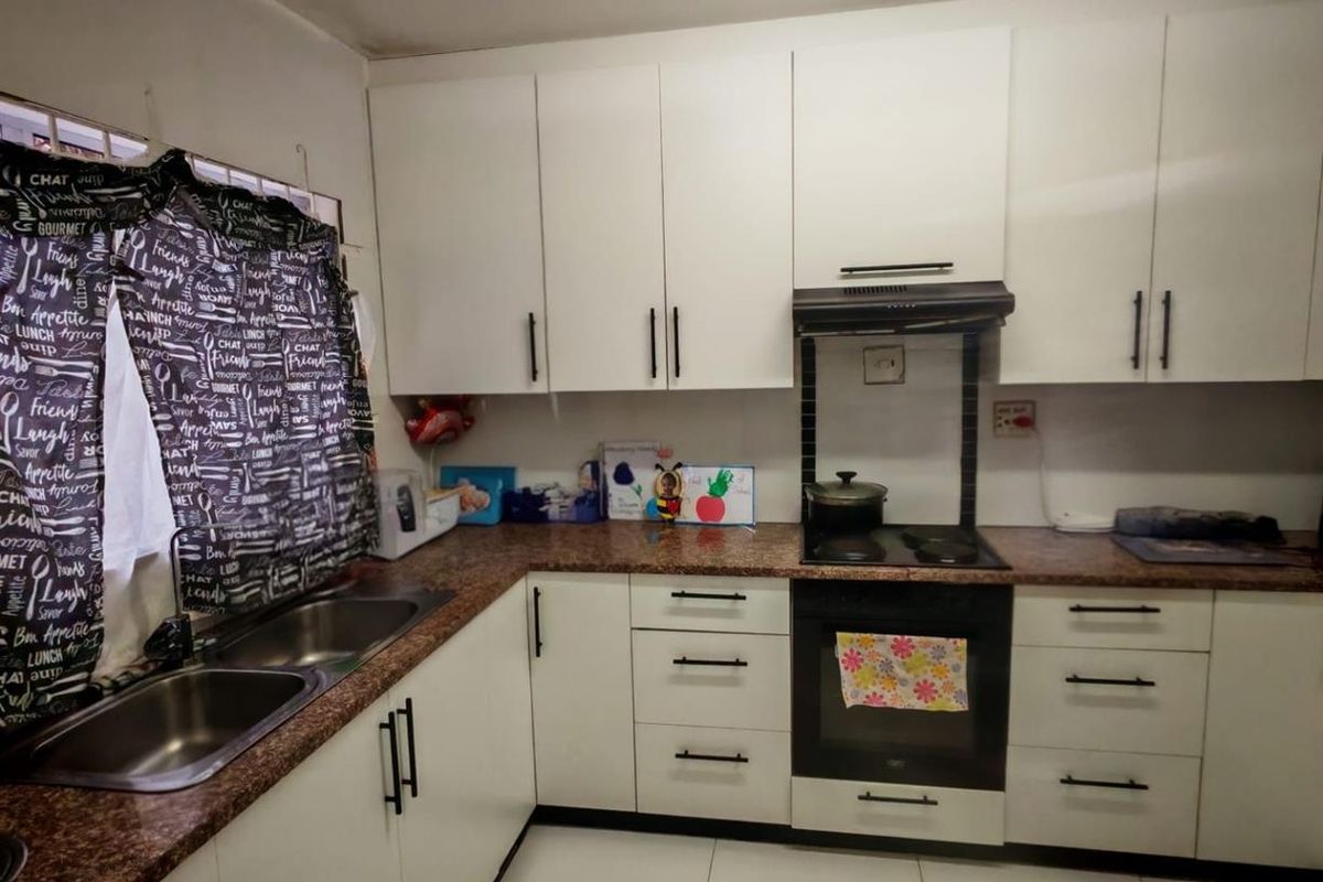 A functional kitchen featuring white cabinetry, granite-look countertops, a double stainless steel sink, and a built-in oven with an extractor fan.