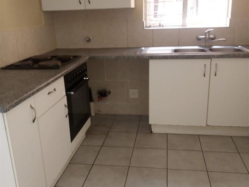 A functional kitchen featuring white cabinetry, a built-in oven, hob, and tiled flooring, offering a clean and practical space for culinary activities.