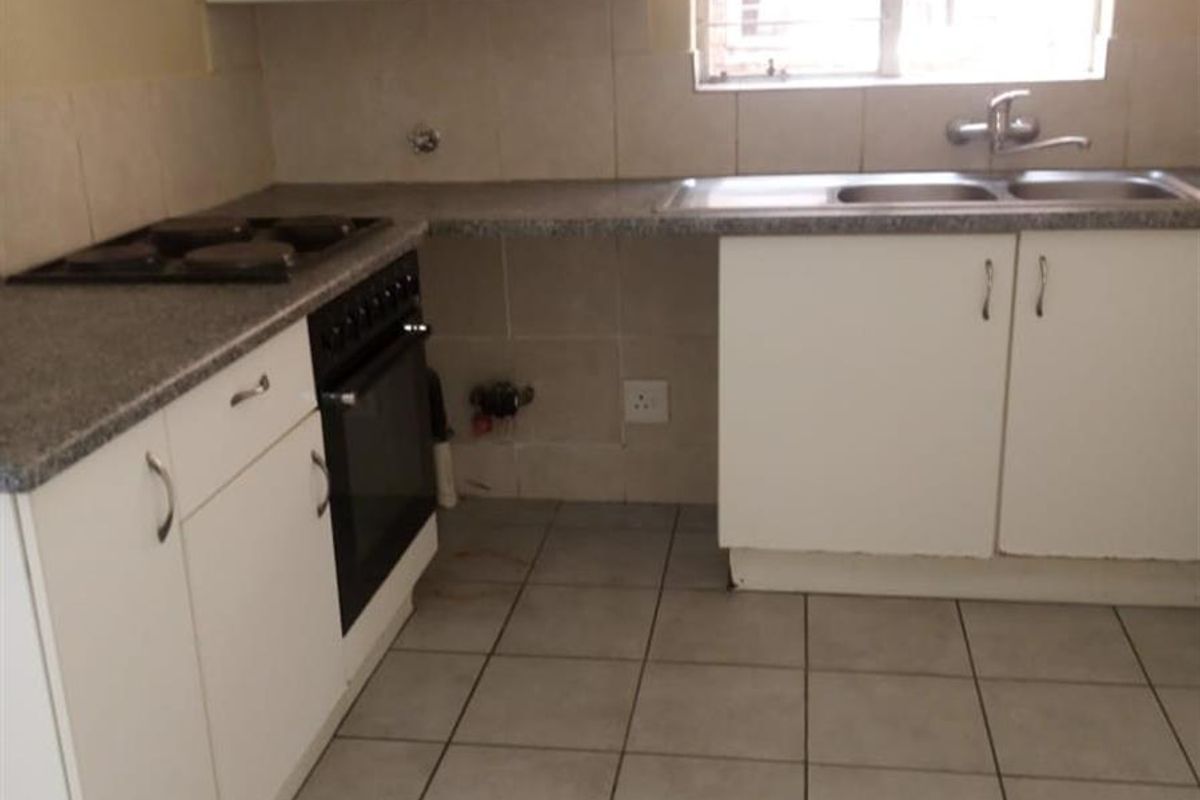 A functional kitchen featuring white cabinetry, a built-in oven, hob, and tiled flooring, offering a clean and practical space for culinary activities.