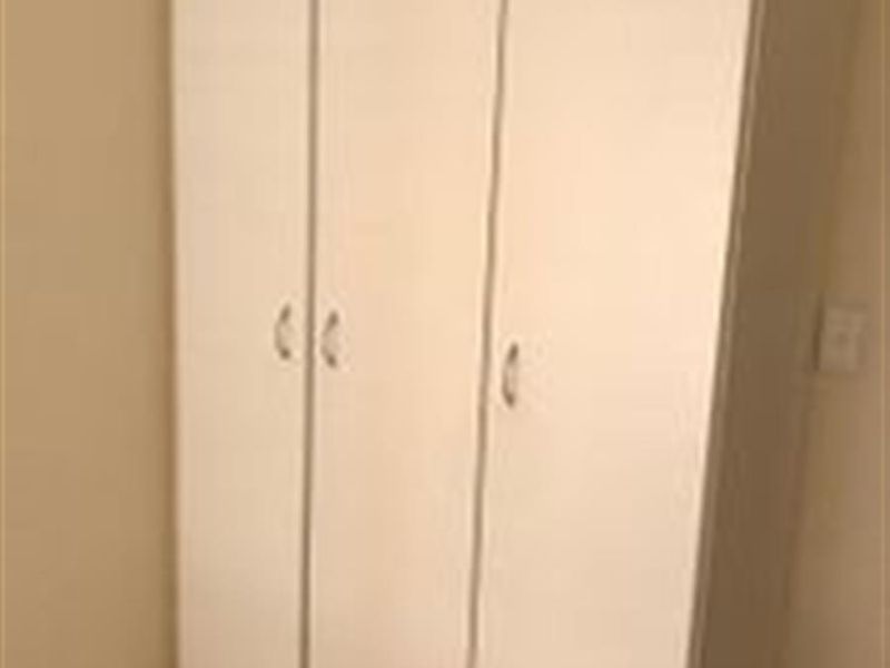 A bedroom featuring a white built-in wardrobe with simple handles, providing functional storage space.