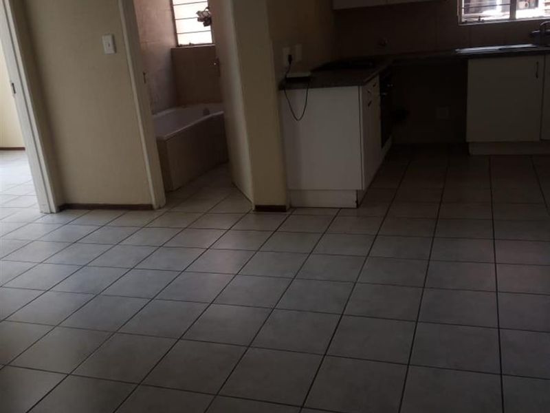 Open plan living area featuring tiled flooring, adjacent kitchen with built-in cabinetry, and access to a bathroom with a built-in bathtub.