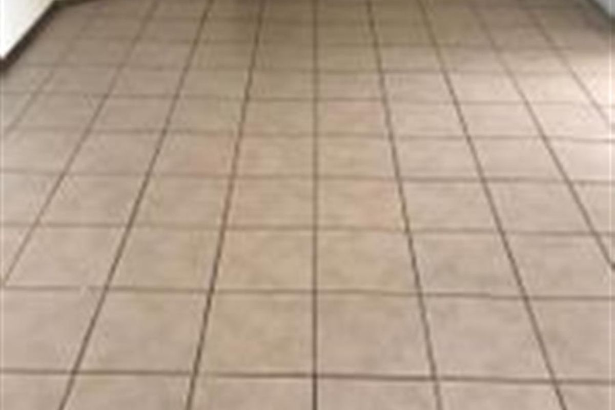 An empty living area featuring neutral ceramic floor tiles and plain walls, providing a blank canvas for interior design.