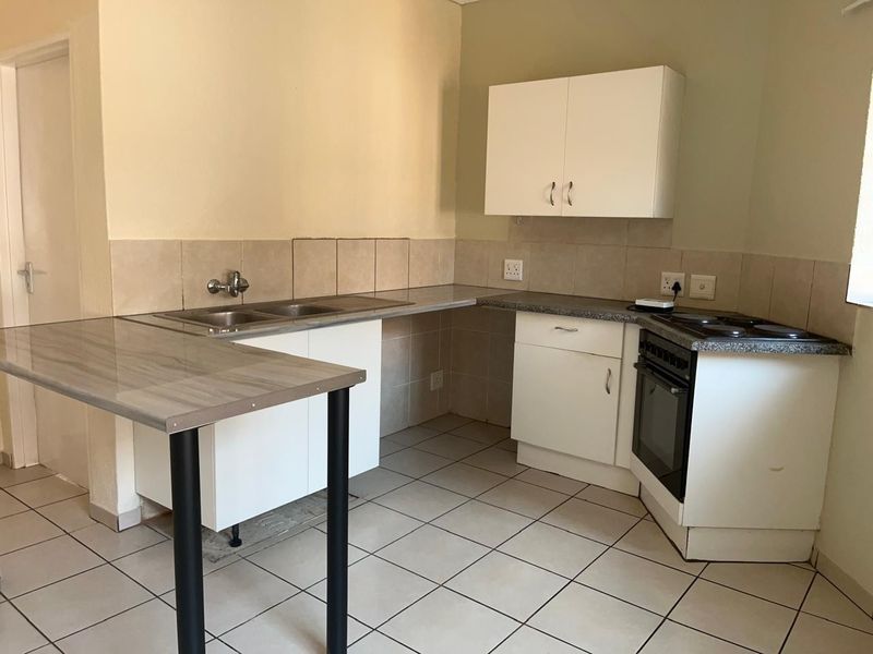 A functional kitchen featuring white cabinetry, laminate countertops, a built-in oven with hob, and tiled flooring, offering a clean and practical workspace.