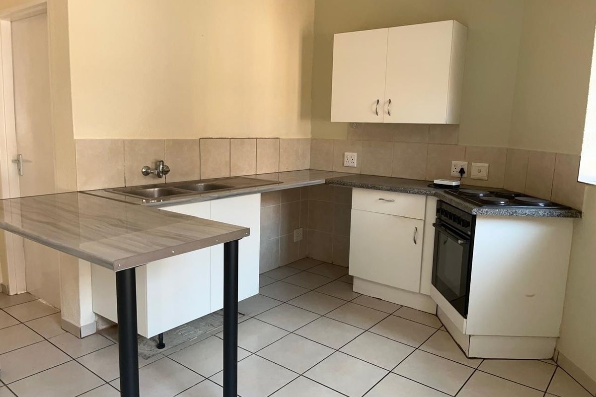 A functional kitchen featuring white cabinetry, laminate countertops, a built-in oven with hob, and tiled flooring, offering a clean and practical workspace.