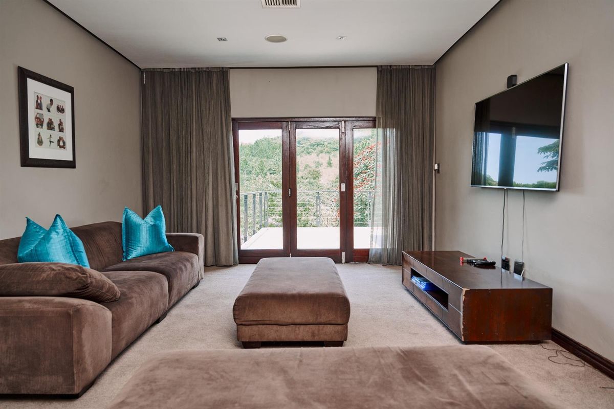 A comfortable living room featuring neutral walls, carpeted flooring, and large glass doors that open onto a balcony with scenic views.