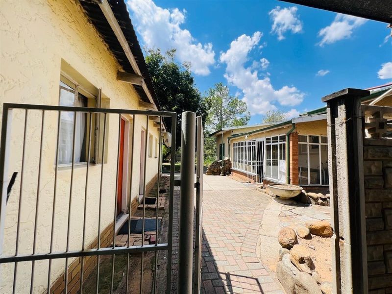 A view of the rear exterior area featuring paved walkways, a metal gate, and access to the main dwelling structure.