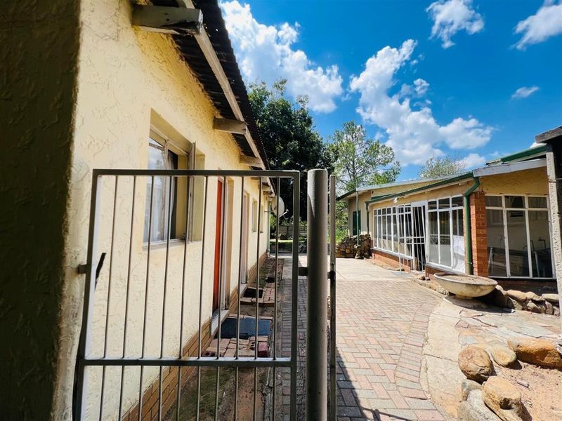 Exterior view of the property showing a paved courtyard area, metal security gate, and access to the side of the house.