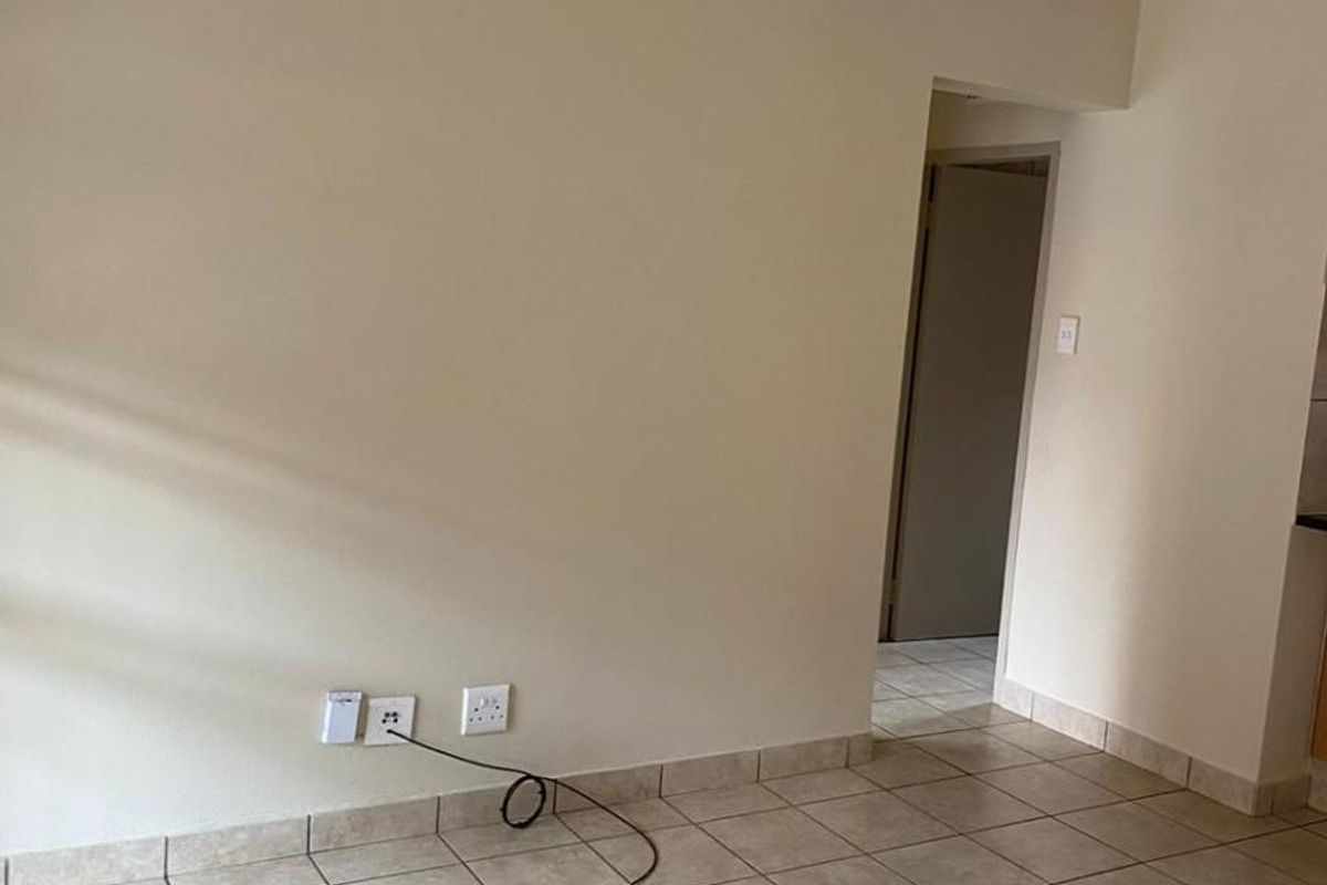 An empty living area featuring neutral wall paint and ceramic floor tiles, providing a clean and versatile space for personalization.