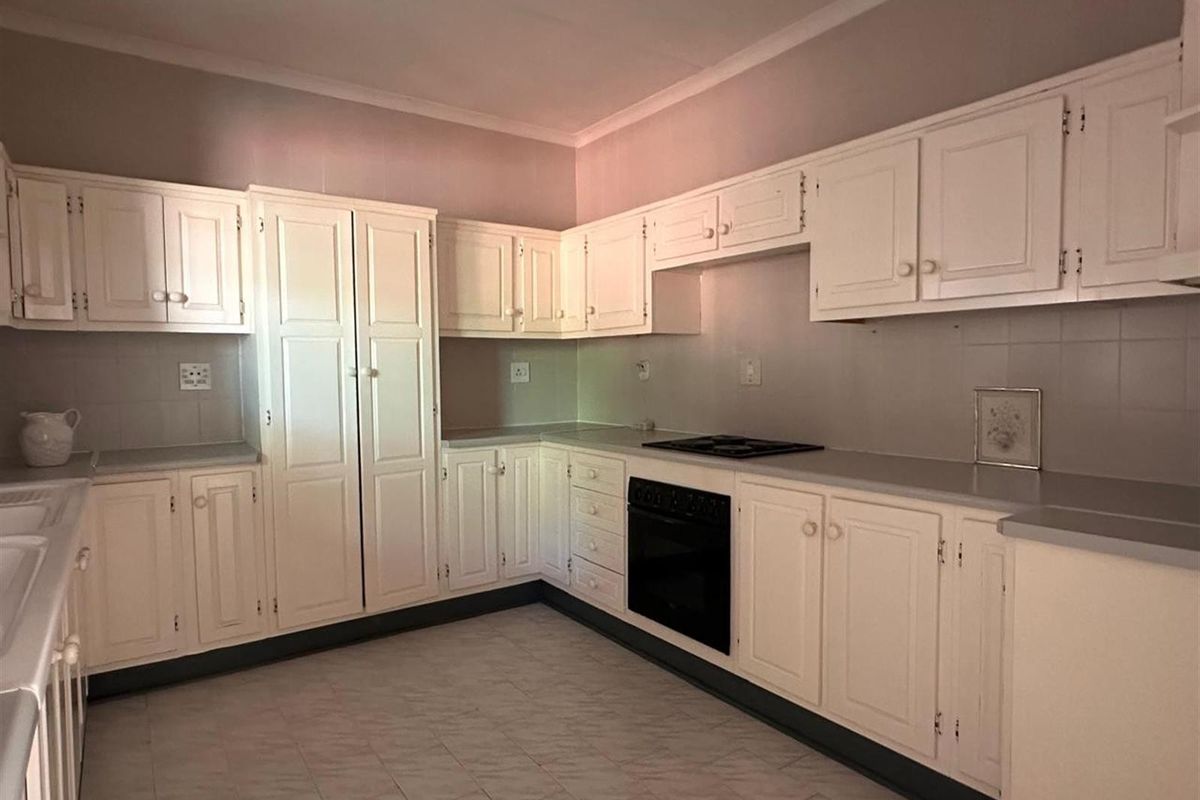 A functional kitchen featuring white cabinetry, a built-in oven, and a cooktop with ample counter space and tiled splashbacks.