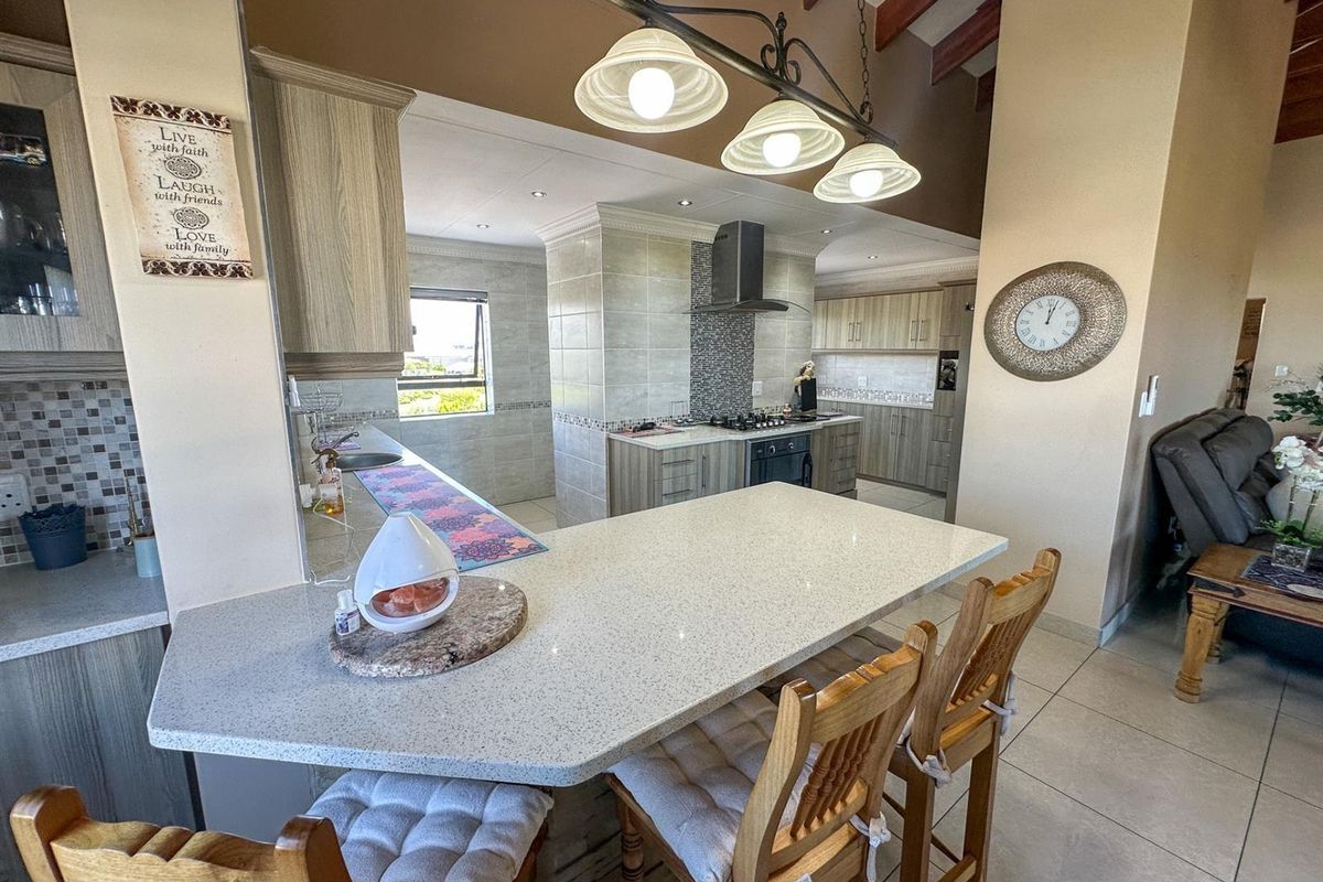 Spacious kitchen featuring a stone breakfast bar, built-in cabinetry, gas hob, extractor fan, and exposed timber ceiling beams.