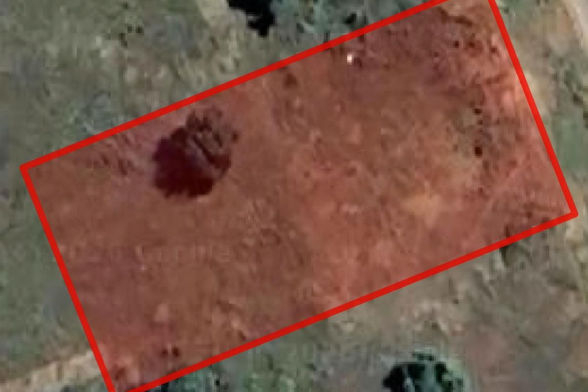 An aerial view of a vacant residential plot of land, highlighting the property boundaries and surrounding terrain.