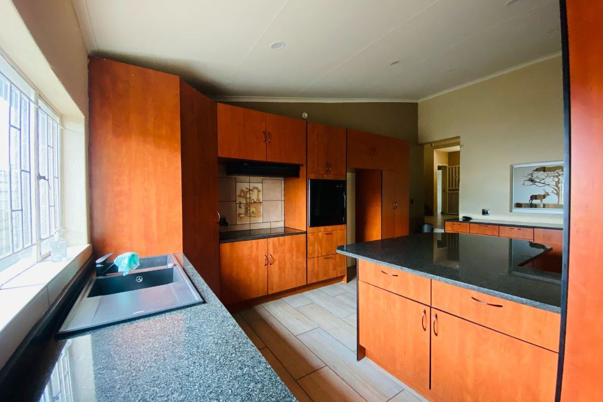 A functional kitchen featuring wooden cabinetry, granite countertops, a central island, and built-in oven with extractor fan.
