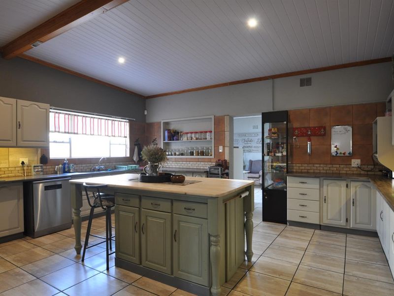 Spacious kitchen featuring a central island with a wooden countertop, tiled flooring, recessed lighting, and ample built-in cabinetry with integrated storage solutions.