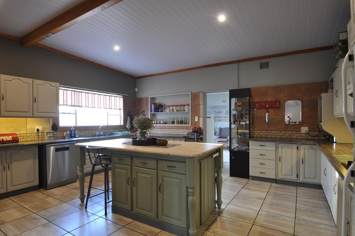 Spacious kitchen featuring a central island with a wooden countertop, tiled flooring, recessed lighting, and ample built-in cabinetry with integrated storage solutions.
