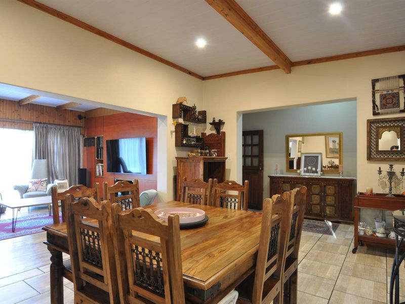 Spacious dining area featuring tiled flooring and exposed timber ceiling beams, seamlessly flowing into an adjacent living space.