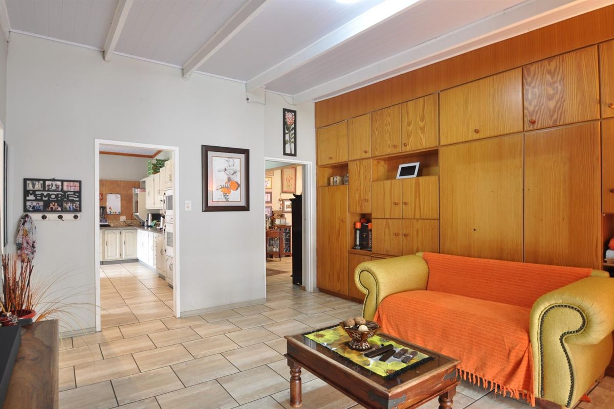 A living room featuring built-in wooden cabinetry and tiled flooring, with an open doorway leading to the kitchen area.