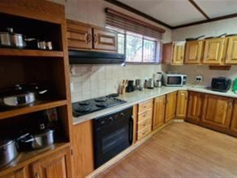 A functional kitchen featuring traditional wooden cabinetry, laminate countertops, a built-in oven, and an electric hob with an extractor fan.