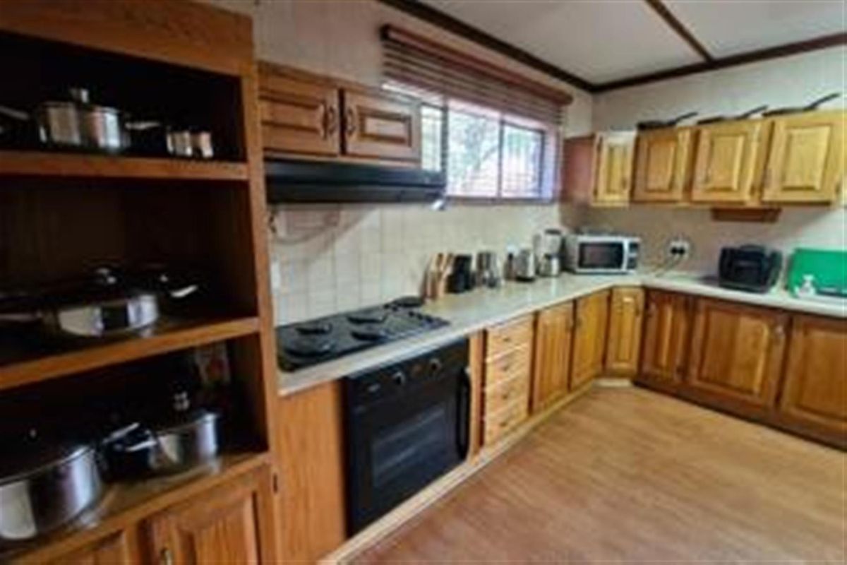 A functional kitchen featuring traditional wooden cabinetry, laminate countertops, a built-in oven, and an electric hob with an extractor fan.