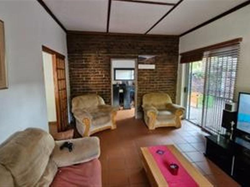 A living room featuring exposed brick walls, tiled flooring, and a sliding glass door providing access to the exterior.