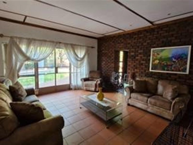 A living room featuring an exposed brick feature wall, tiled flooring, and large sliding glass doors providing access to the outdoor area.